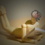 Piccolo manichino che legge un libro sul controllo mentale
